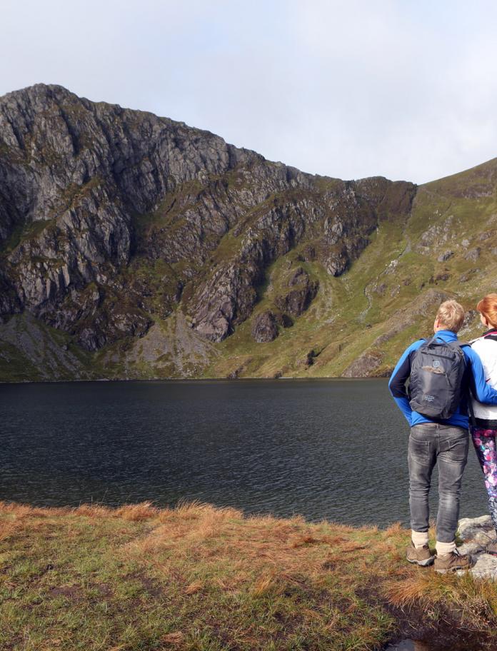 Two people looking over a lake towards the top of Cader Idris.