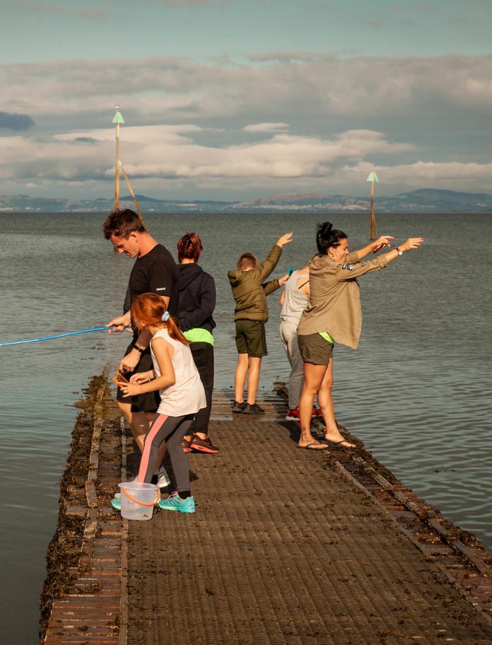 People crabbing off a small seaside jetty.