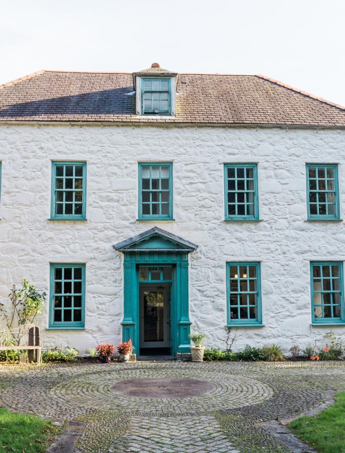 Exterior of Tŷ Newydd - a white house with light blue woodwork
