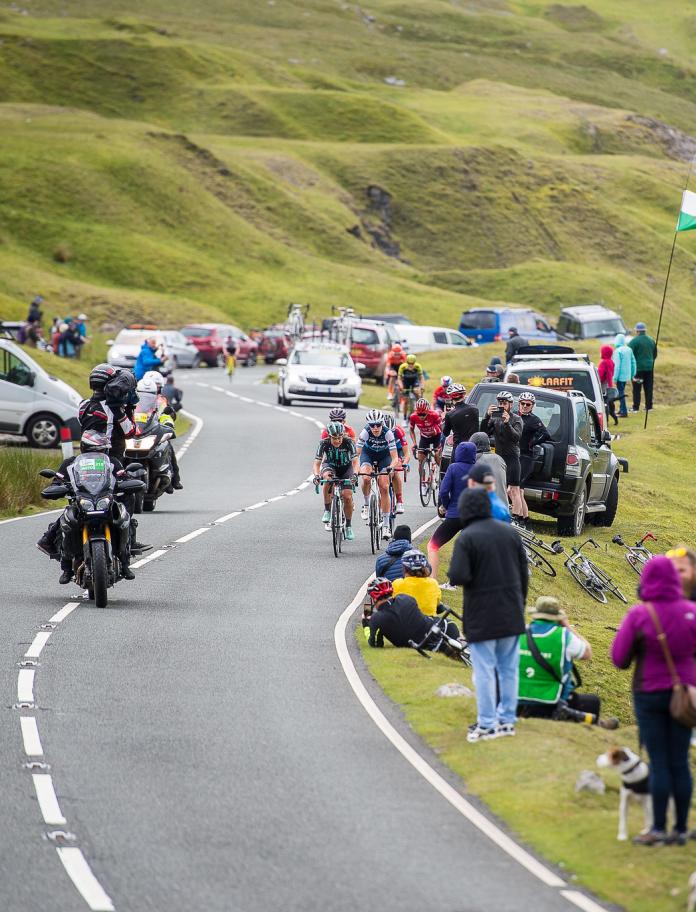 Cyclists and spectators lining a mountain road.