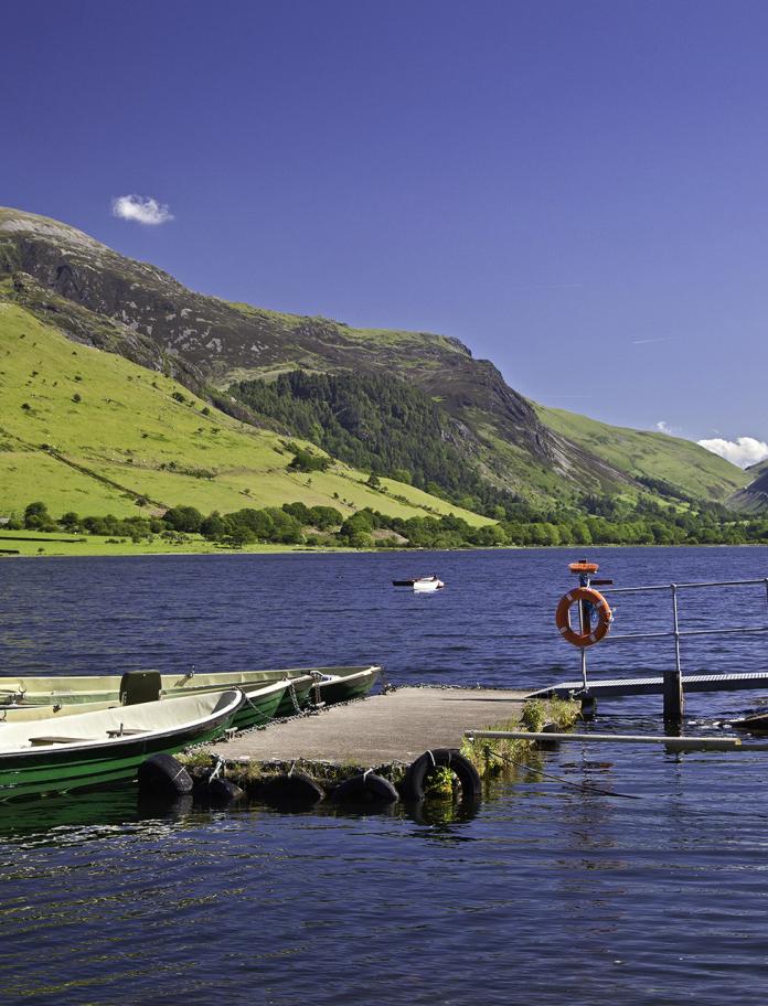 A large lake in a valley with a jetty and rowing boat.