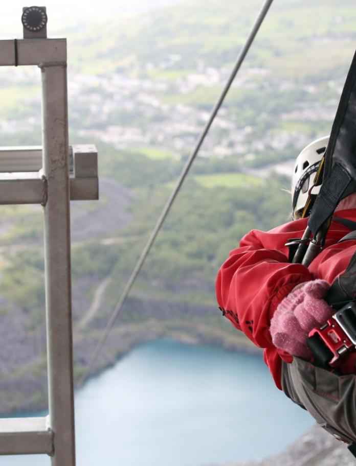 a man strapped into a zipwire overlooking a large quarry