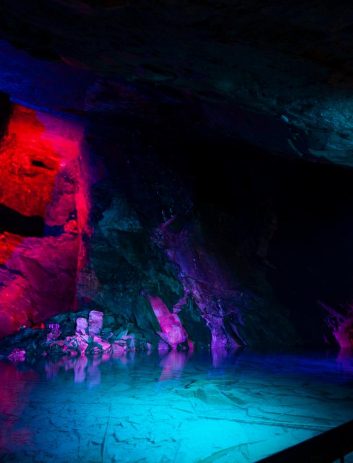 Slate cavern and natural spring water lit up with brightly coloured lights.