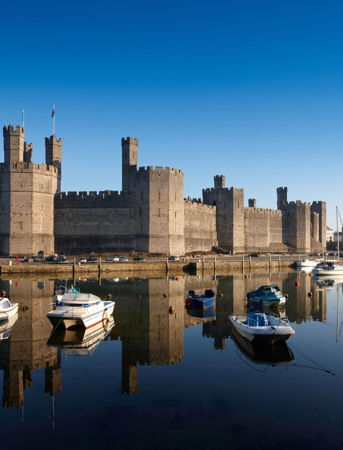 Exterior view of castle from the South with boats and water.