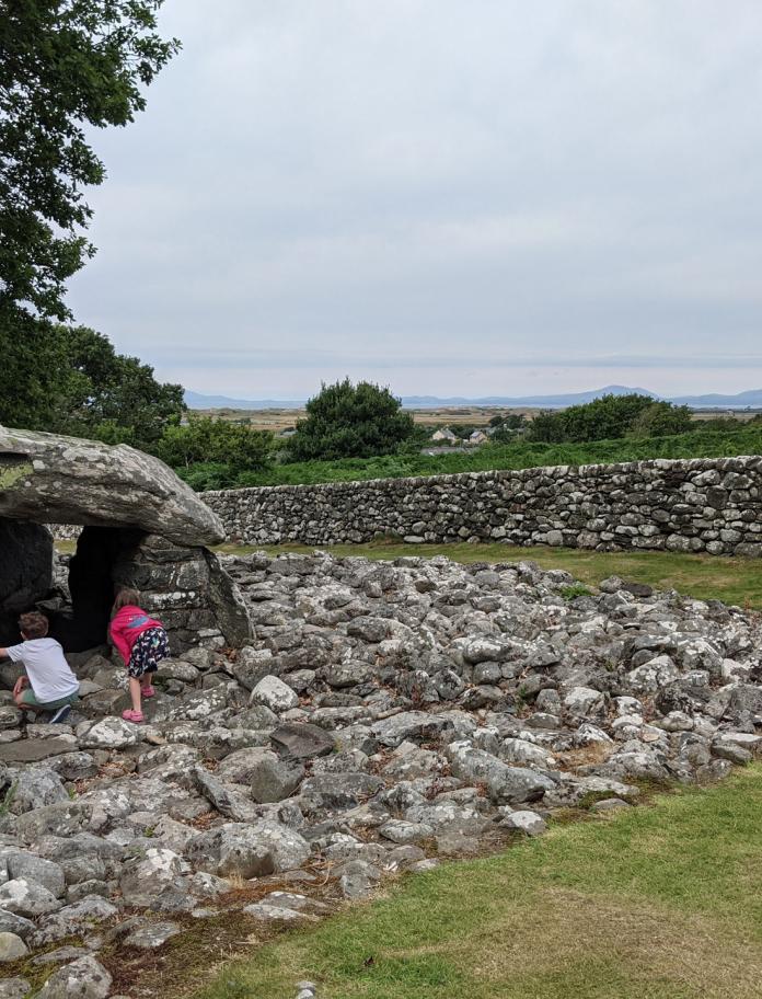 Two children exploring a stone burial chamber.