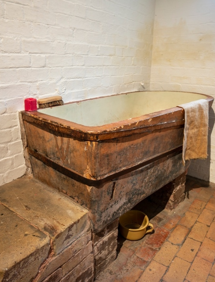 Interior of old gaol cell, with wooden furniture.