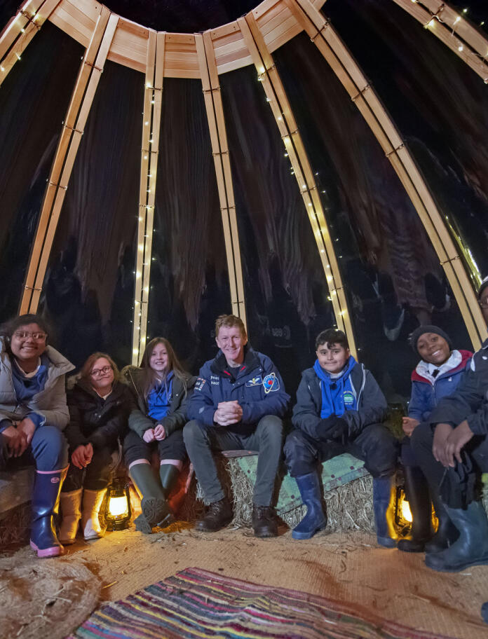 Sechs Kinder sitzen mit Tim Peake in einem Zelt zusammen