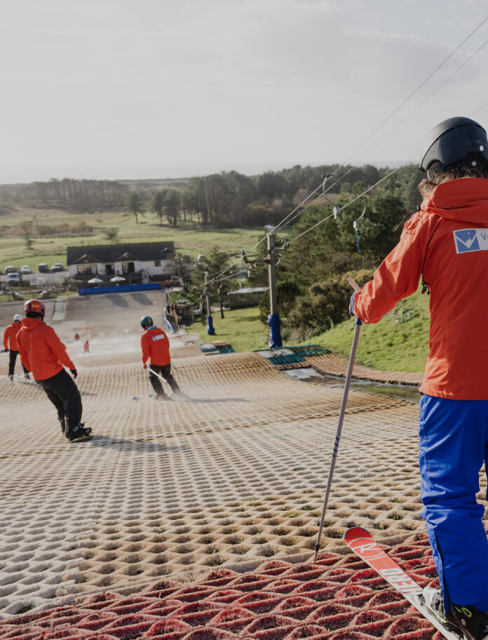 Several people skiing down a dry ski slope.