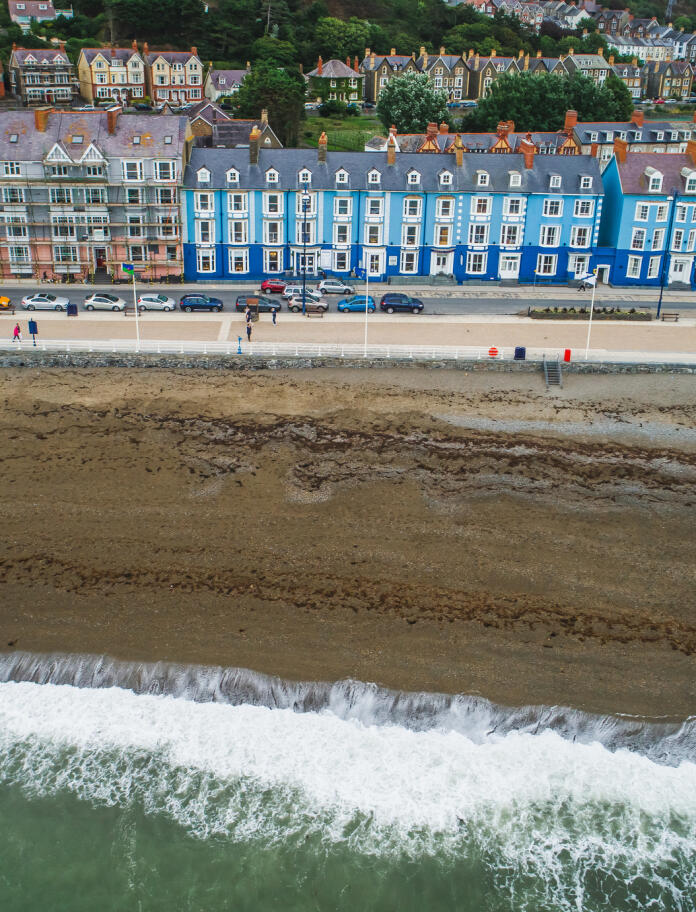 A view of different colour houses looking out to a sandy beach and sea.