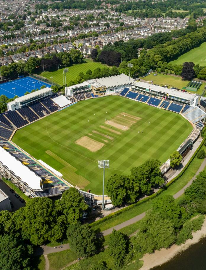 A cricket stadium by a river from above.