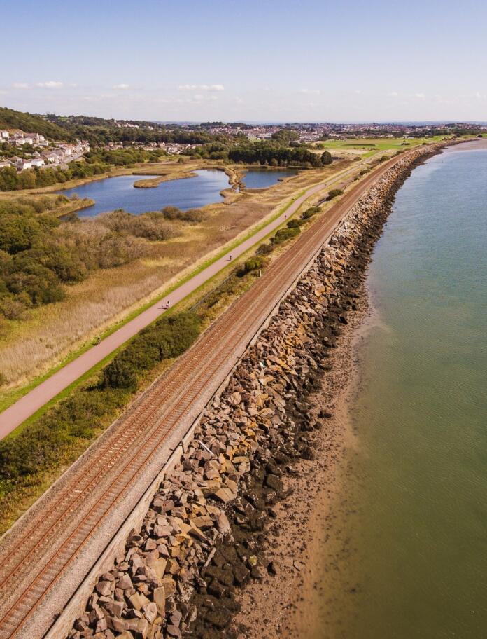 An aerial view of a railway line and footpath along a river.