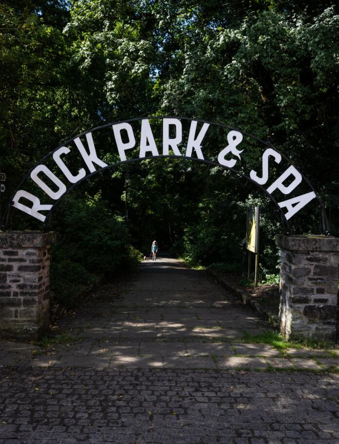 Entrance to a park with metal signage over the path stating 'Rock Park & Spa'.