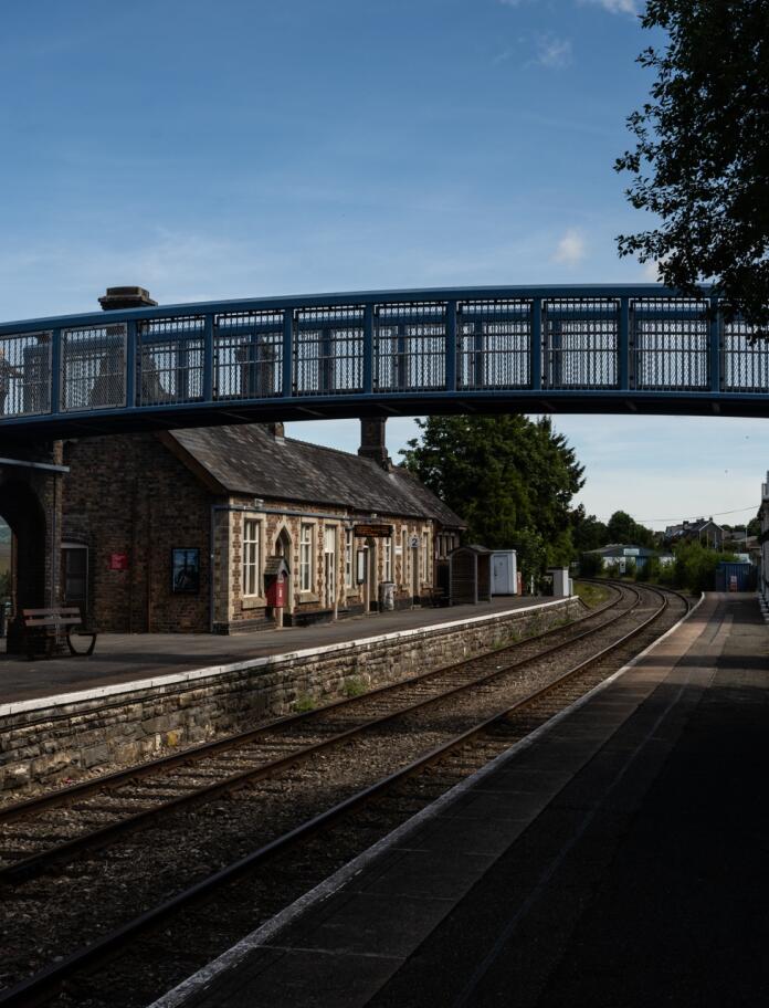 A rural railway station with a footbridge over the tracks.