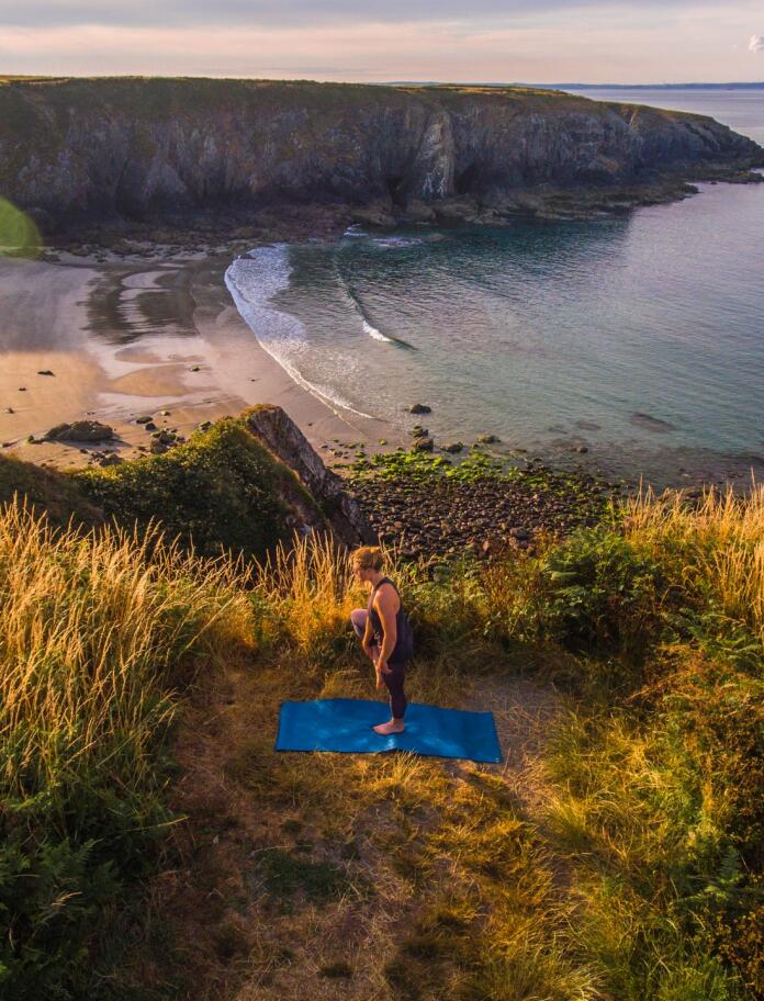 A person practicing yoga overlooking the sea.