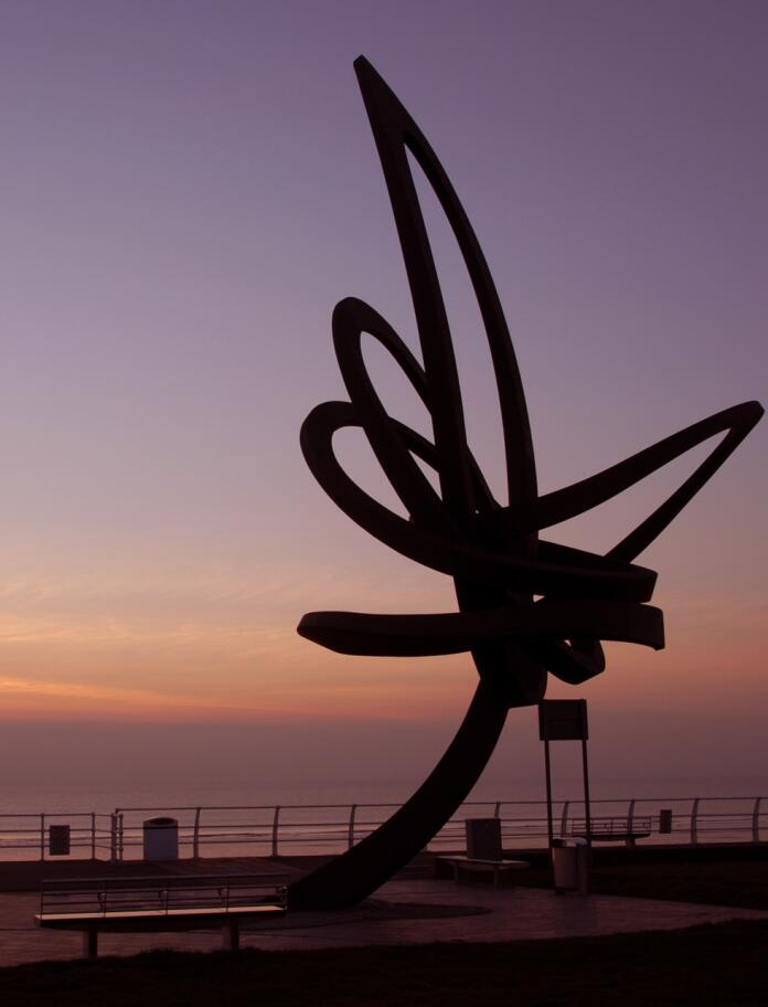 Silhouette of a beachfront sculpture at sunset.