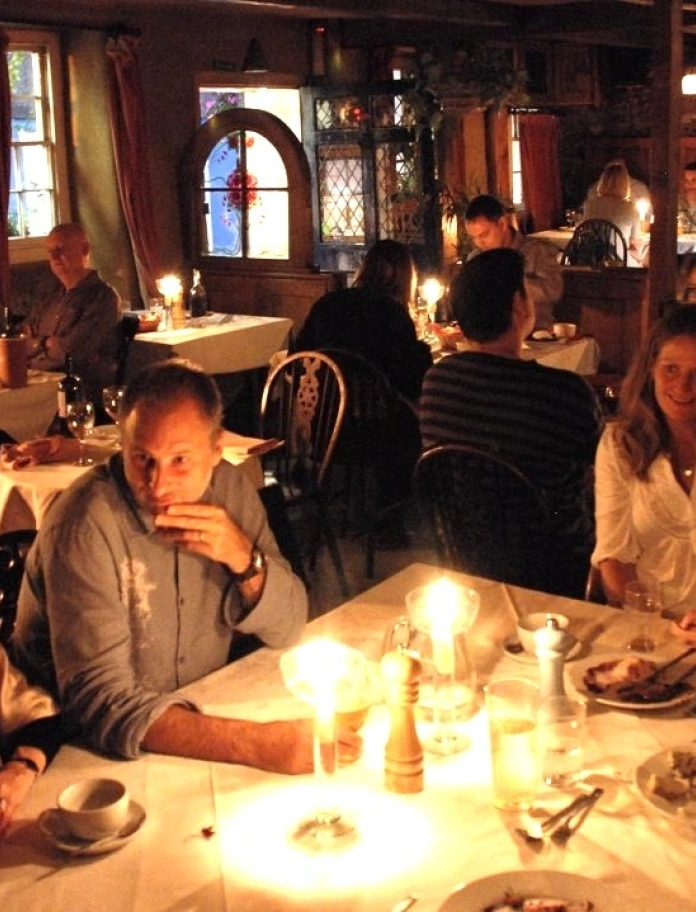 groups of people eating at tables by candlelight.