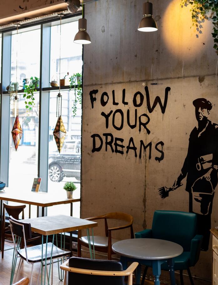 interior of cafe, with graffiti type painting and words follow your dreams on wall.