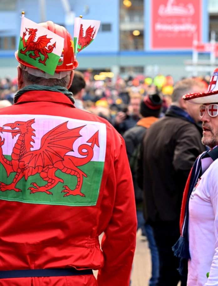 Ein Mann in walisischer Fantracht vor einem Stadion.