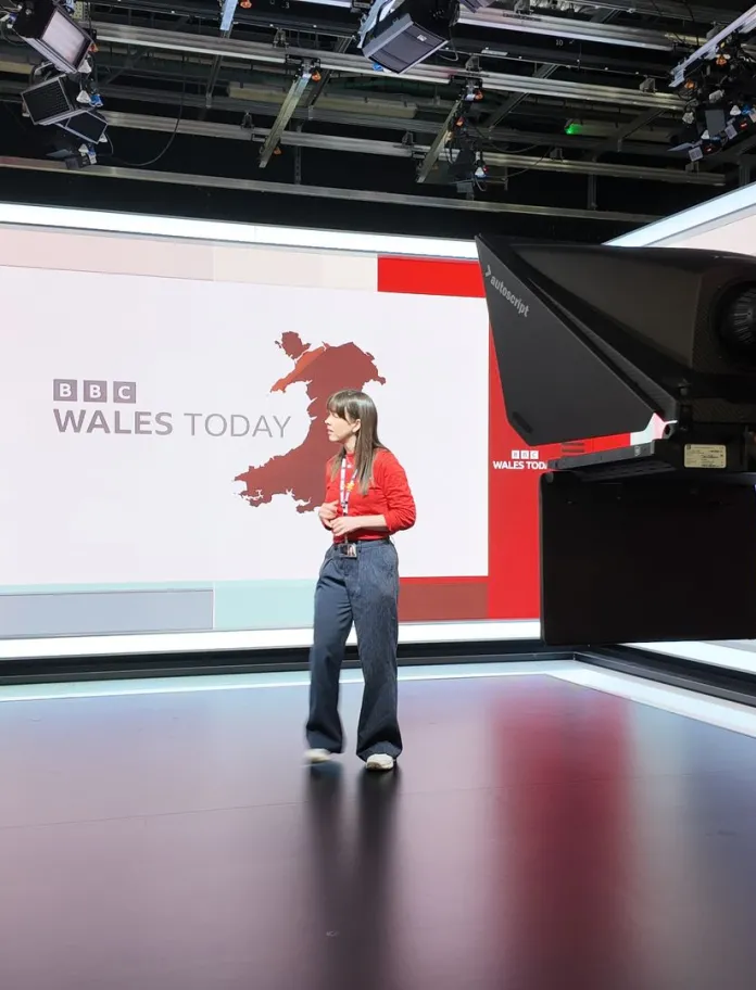 tour of BBC with people watching woman in front of screen and camera.