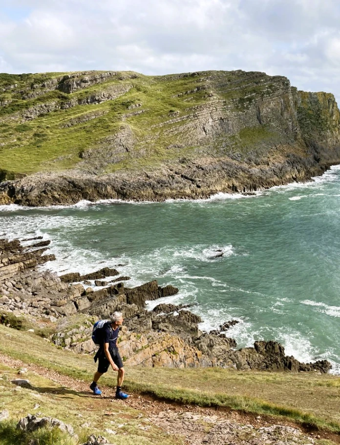Wanderer mit Rucksack auf einem Küstenwanderweg am Meer.