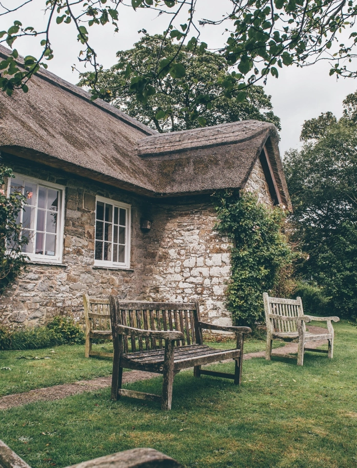 exterior of thatched roofed church with benches.