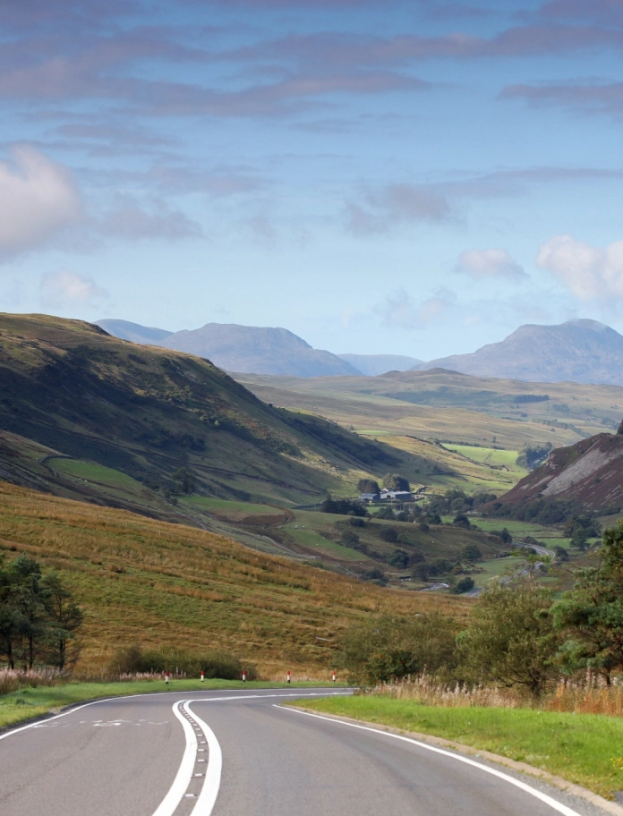 Eine Straße hinunter in ein Tal mit Bergen im Hintergrund.