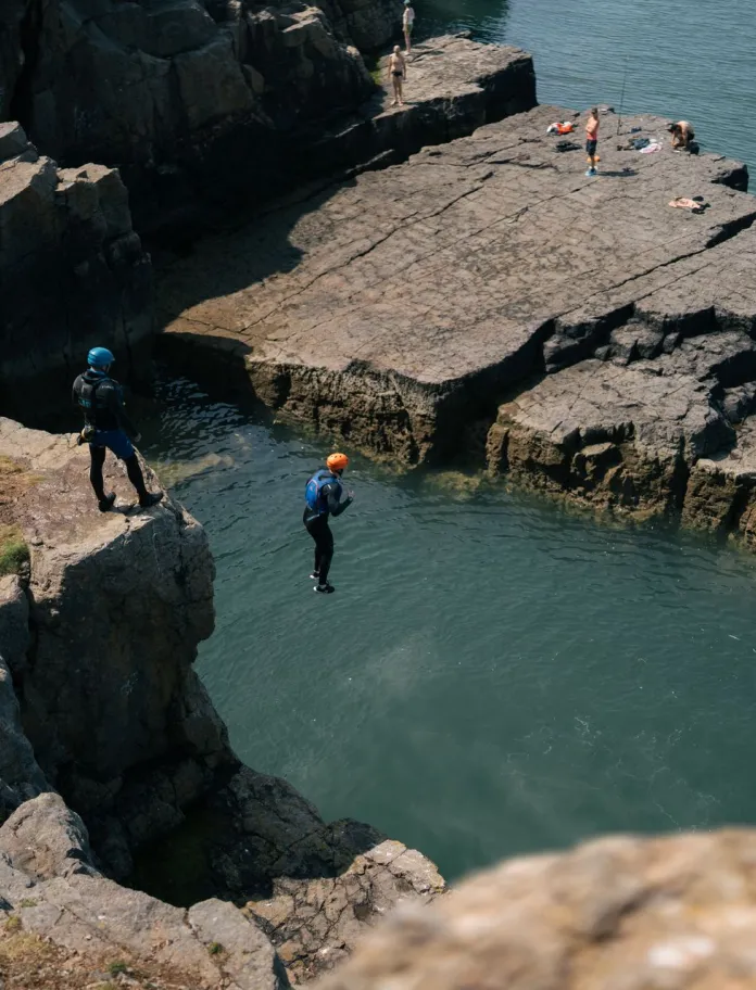 Coasteering - a person jumping into the sea from a cliff.