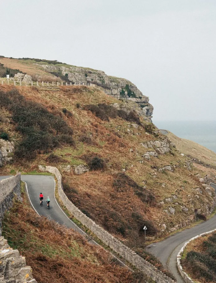 Cyclists riding up a steep winding road on a hillside. 