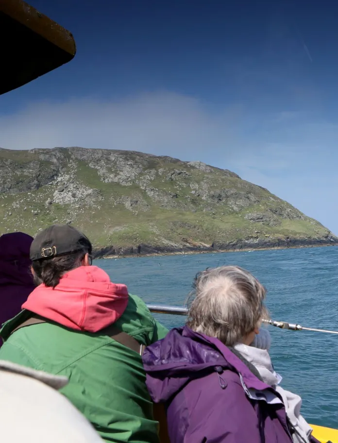 View from a boat of visitors looking towards Bardsey Island’s rugged cliffs and sea