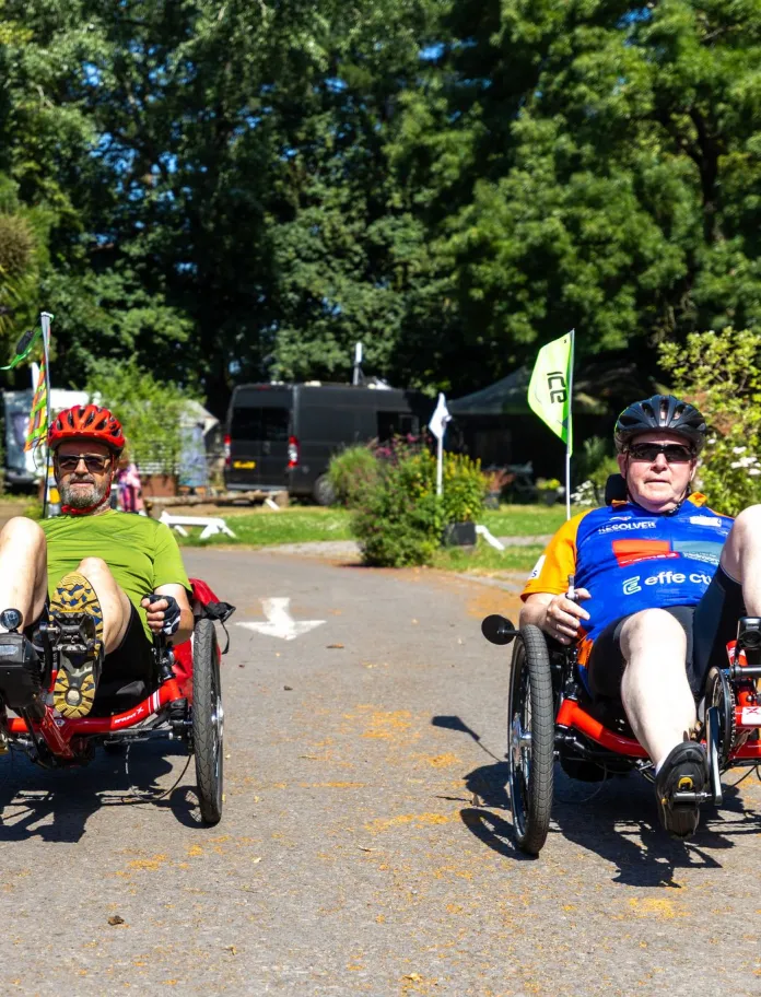 Two cyclists on a pathway in a park.