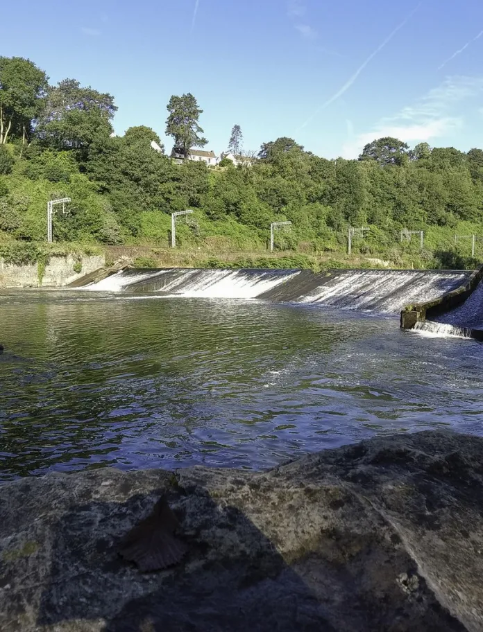 Radyr Weir on the River Taff in Cardiff, framed by rocks and trees with water cascading across the broad weir.