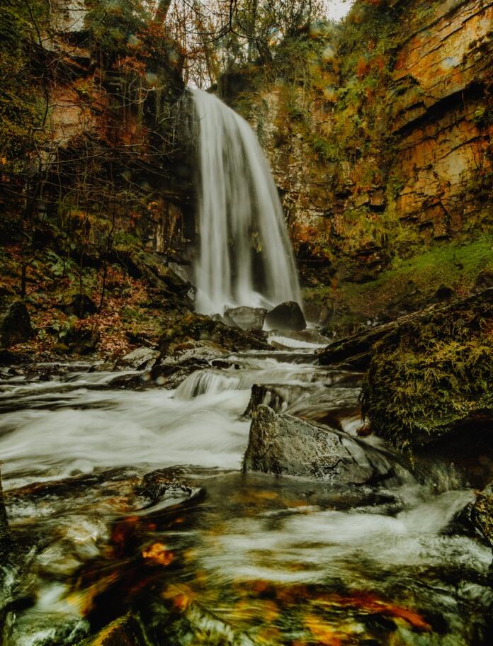 A rushing waterfall in autumnal woodlands.