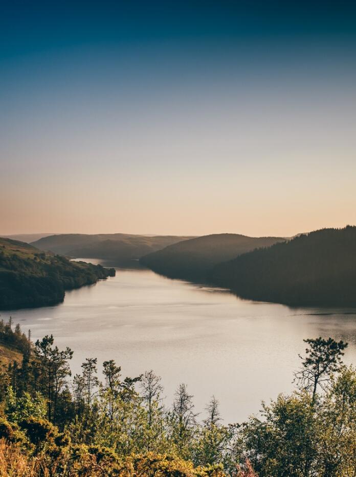 A reservoir surrounded by hills at dusk.