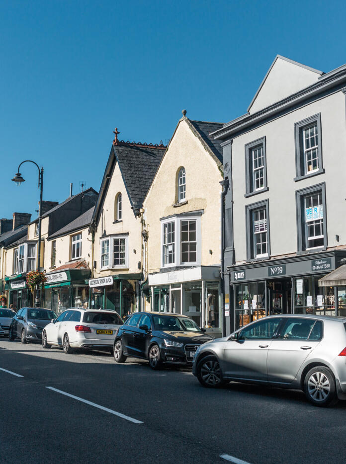 Photo of Cowbridge High Street taken from opposite side of the road with parked cars in shot.