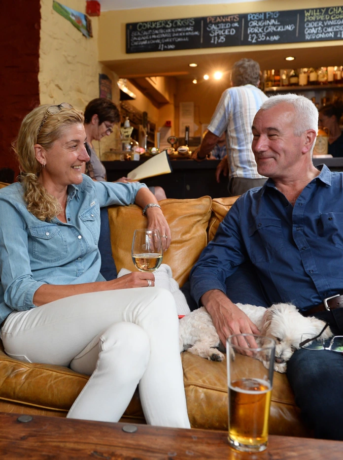 Couple relaxing on a leather sofa in the Felin Fach Griffin with a drink.
