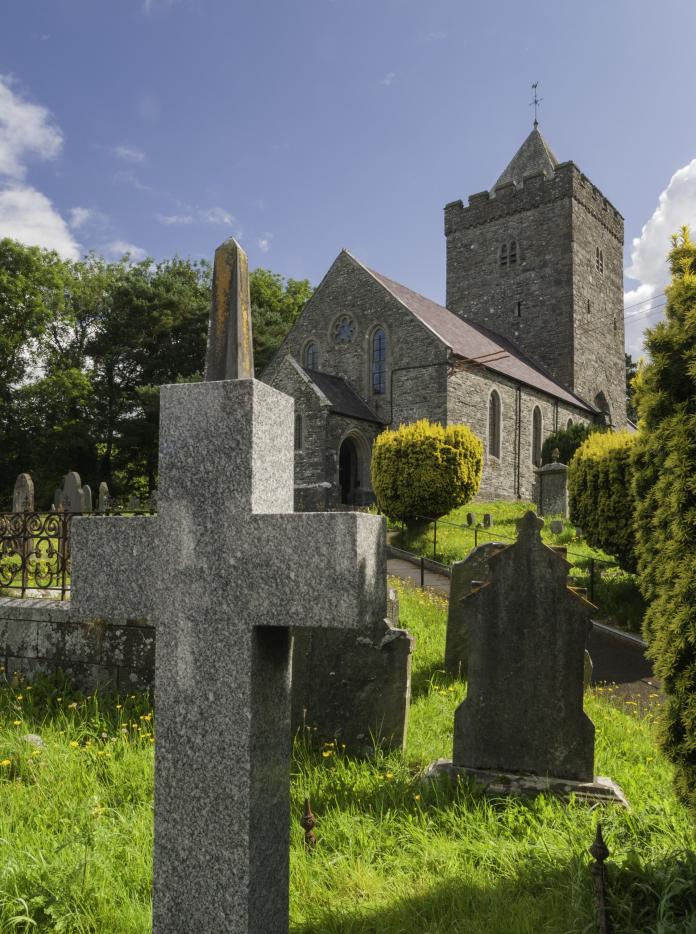St David's Church and the graveyard with a cross and gravestones in the foreground.
