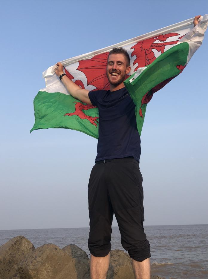 Ash Dykes holding a Welsh flag above his head.