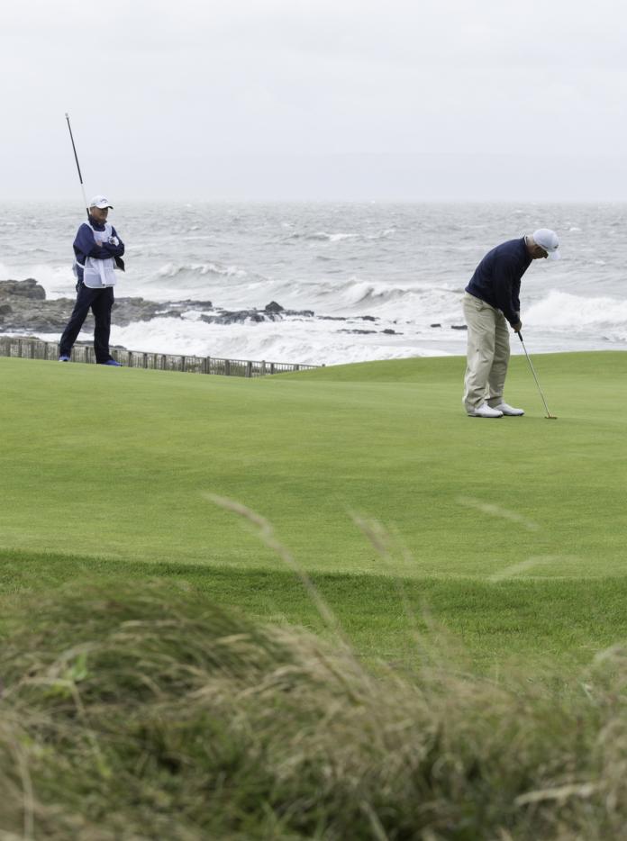 3 people playing golf next to the sea