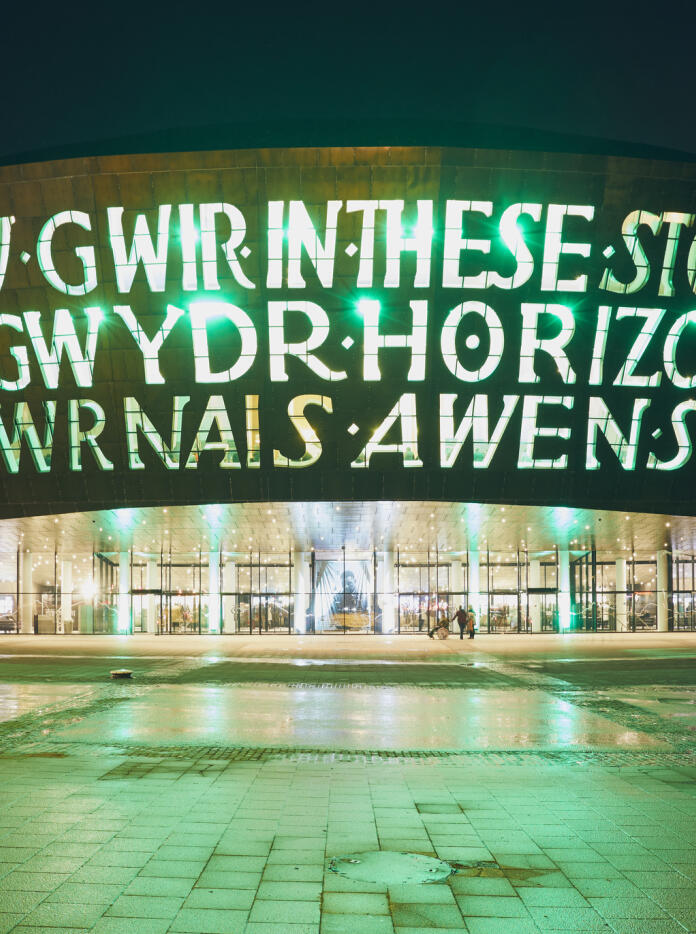 Large building with light up letters saying 'In these stones horizons sing'
