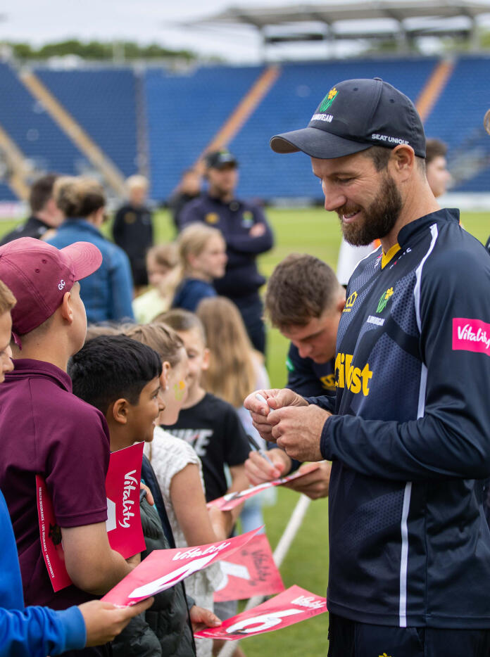A male cricketer signing autographs.