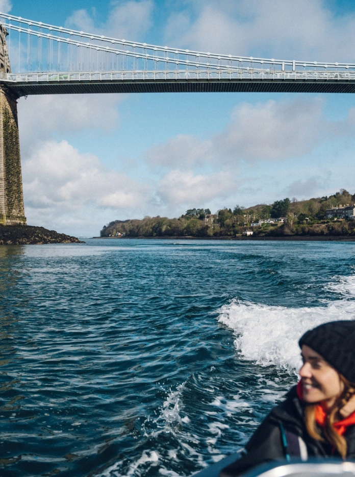 woman on rib boat and bridge in background.