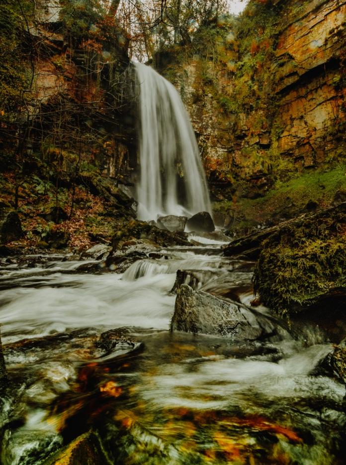 A rushing waterfall in autumnal woodlands.