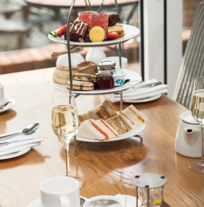 Sandwiches and cakes on a three tiered plate with afternoon tea.