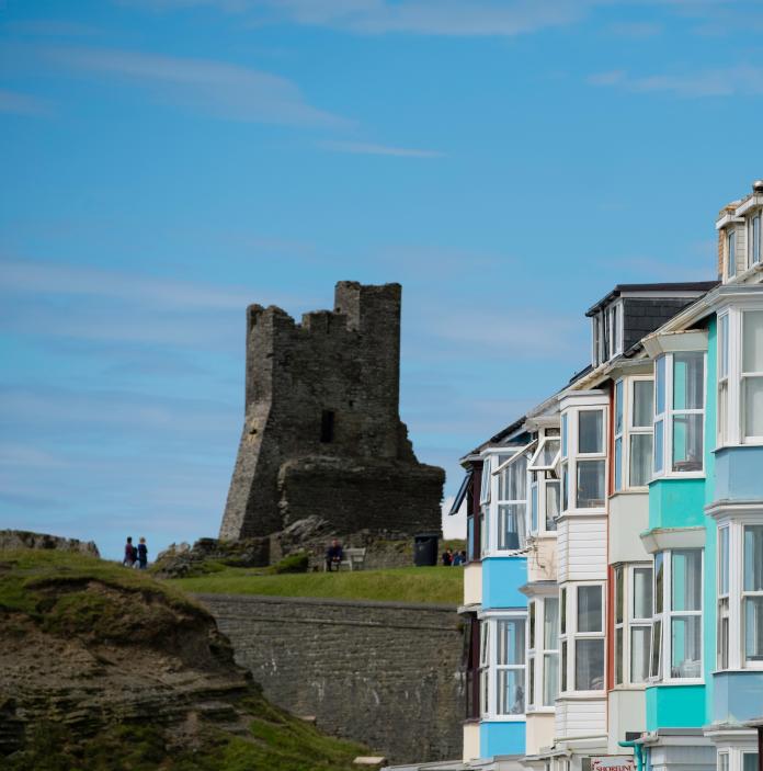 Bild von Aberystwyth Castle und bunten Häusern am Meer.