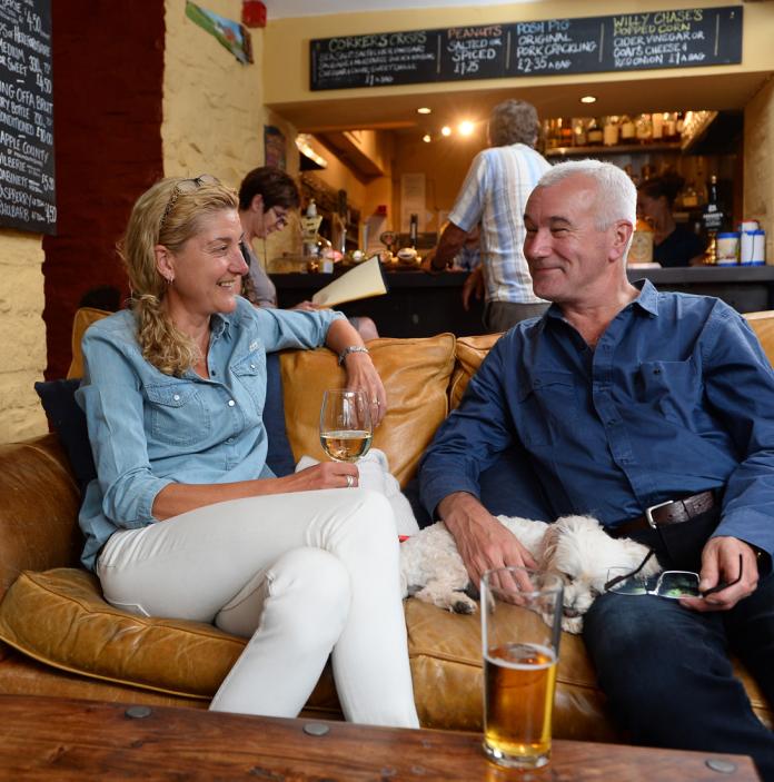 Couple relaxing on a leather sofa in the Felin Fach Griffin with a drink.