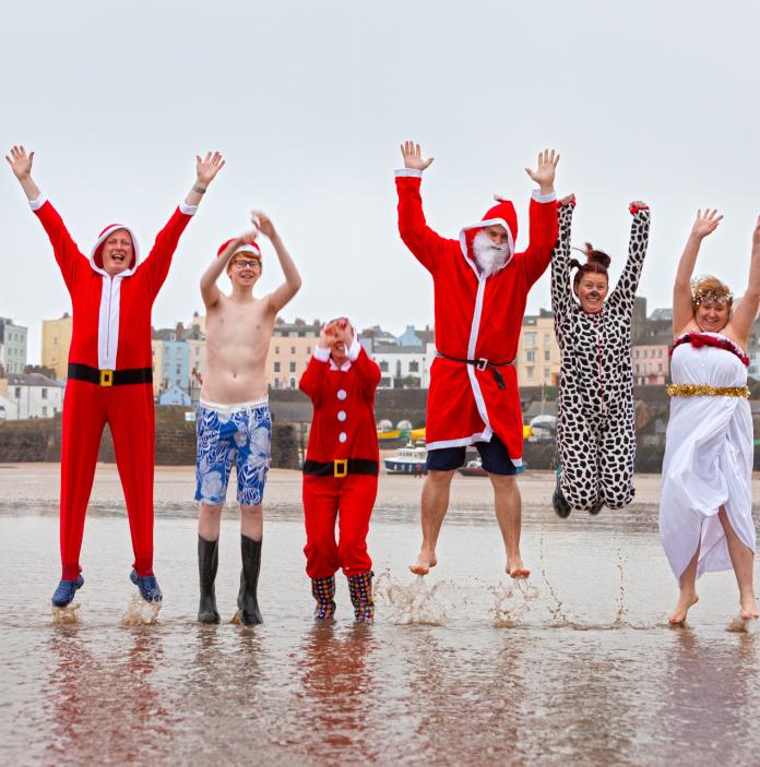 Swimmers jumping in Santa Claus / Father Christmas costumes.