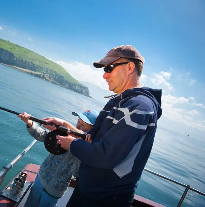 Man fishing with sun (from stern of fishing boat) Off the coast of Anglesey 