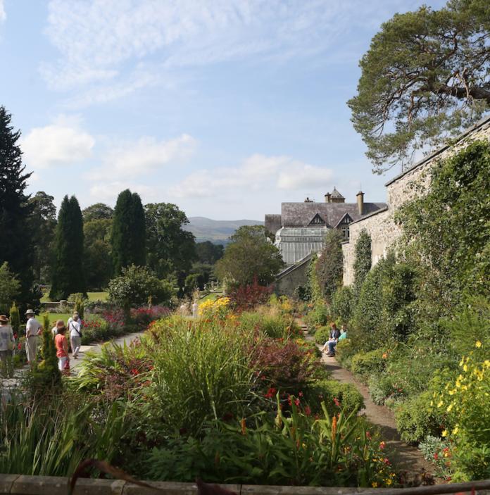 Walled gardens with flowers and plants and people walking at Bodnant Garden.