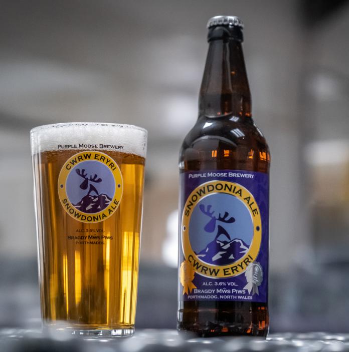 A glass of Purple Moose Snowdonia Ale sitting next to its bottle.