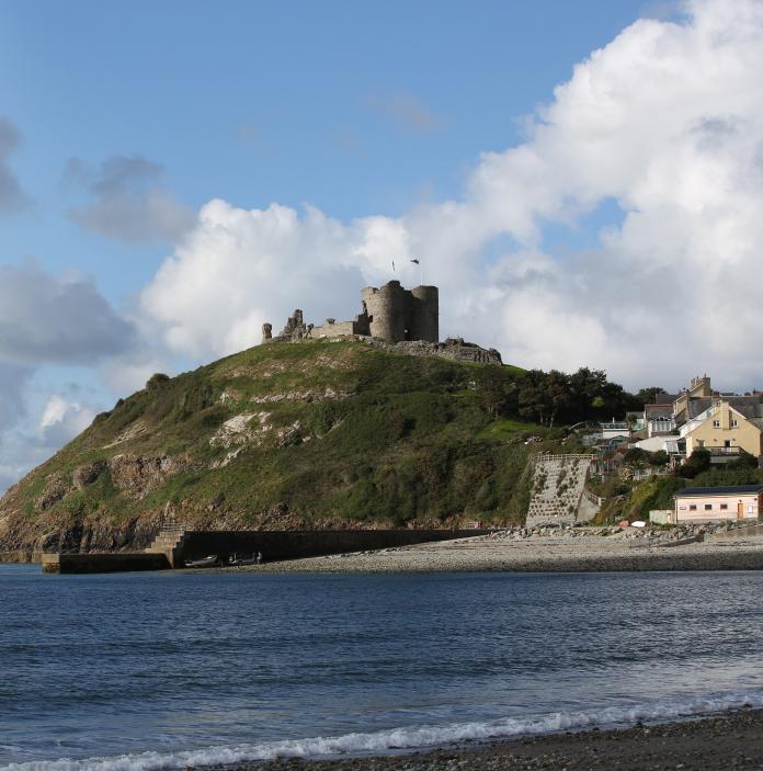 Image of a castle on a hill with the sea in the foreground